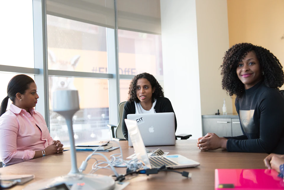 Three women leaders in conversation at a meeting table